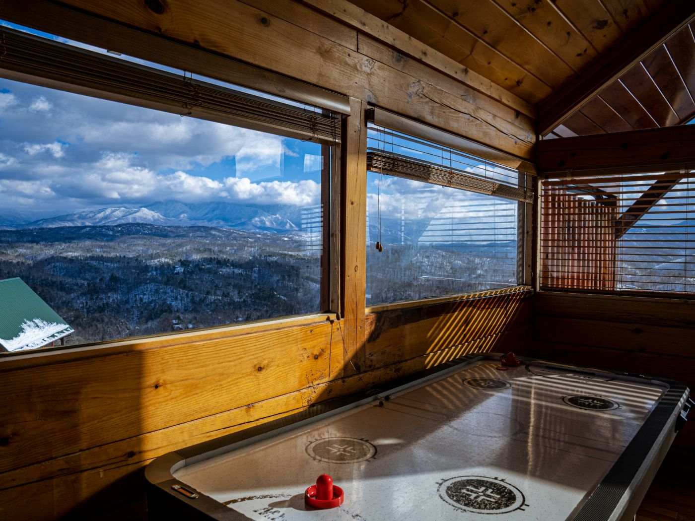 Cabin game room in Big Bear with wood-framed picture windows overlooking snowy mountains