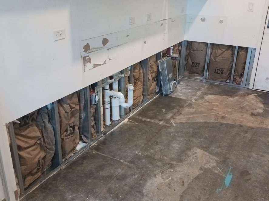 Opened wall on a GC Framing plumbing job showing new PVC drain lines roughed in between metal studs